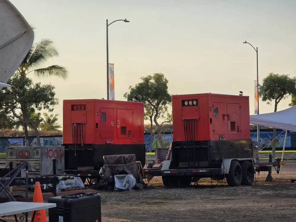 Two red trailer generators on a job site